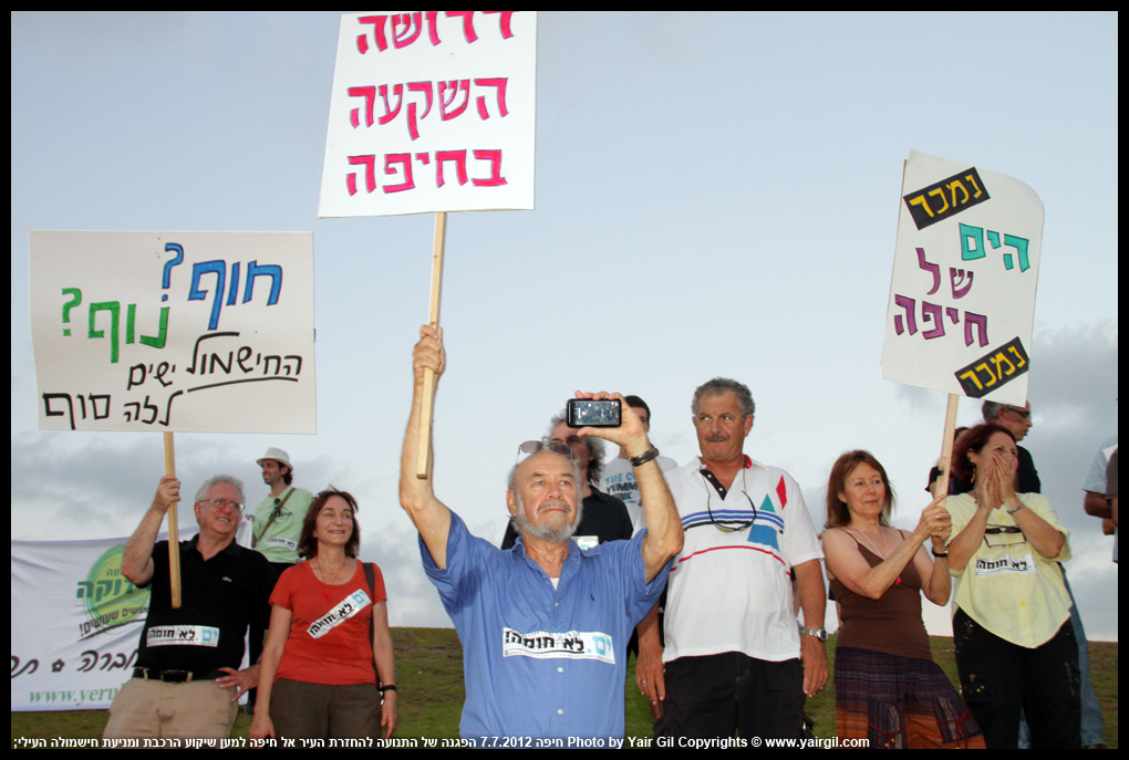 הפגנה של התנועה להחזרת העיר אל חיפה, למען שיקוע הרכבת ומניעת החישמול העילי; התכנית לחשמול הרכבת, תת"ל 18 עומדת לפני מימוש ולפני חריצת גורלה של העיר חיפה. 7.7.2012 חיפה, 