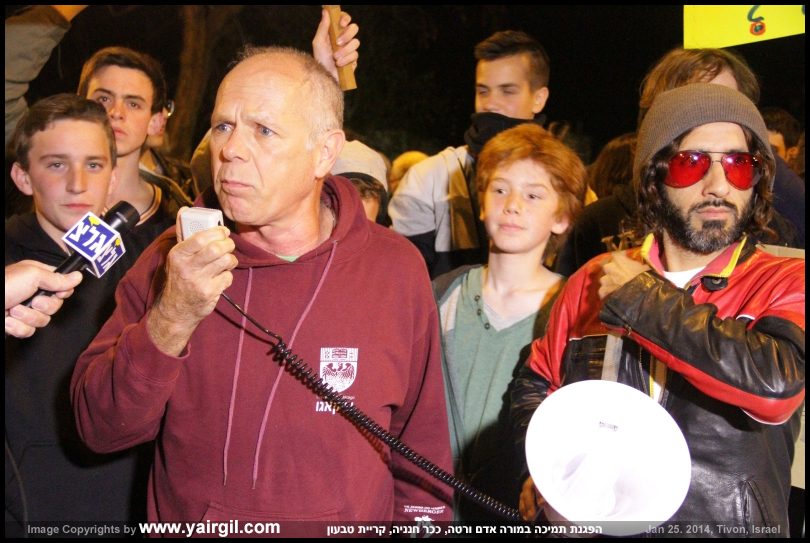 הקומיקאי גדי ווילצ'רסקי מחכה בסבלנות למגפונו -  בהפגנה למען אדם ורטה, טבעון 25.1.2014