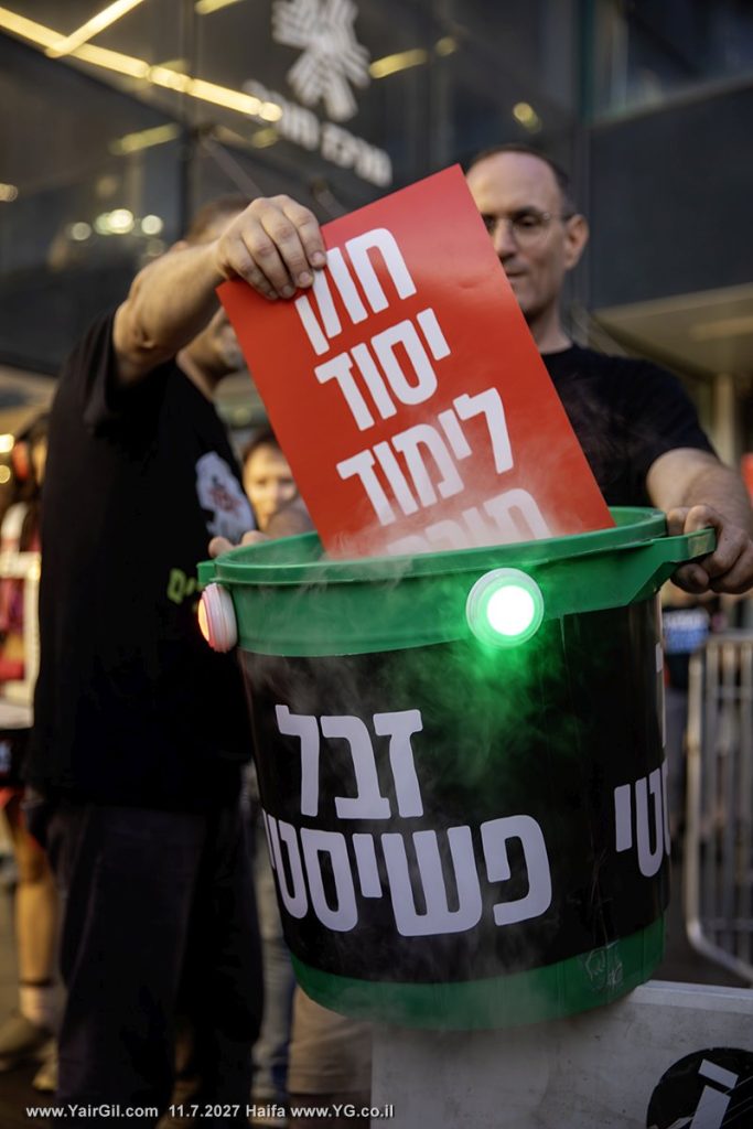 מוצ"ש 11.7.2026 בצומת חורב, חיפה; מיצג קריעת ׳חוק יסוד לימוד תורה׳ לפח הזבל הפאשיסטי; מפה אומרים לך ממשלת ישראל: שכאן בחיפה לא יהיה מעמד אצולה