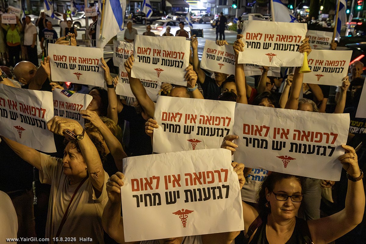 על השלטים כתוב: לרפואה אין לאום - 
לגזענות יש מחיר. צומת חורב 15.8.2026 חיפה